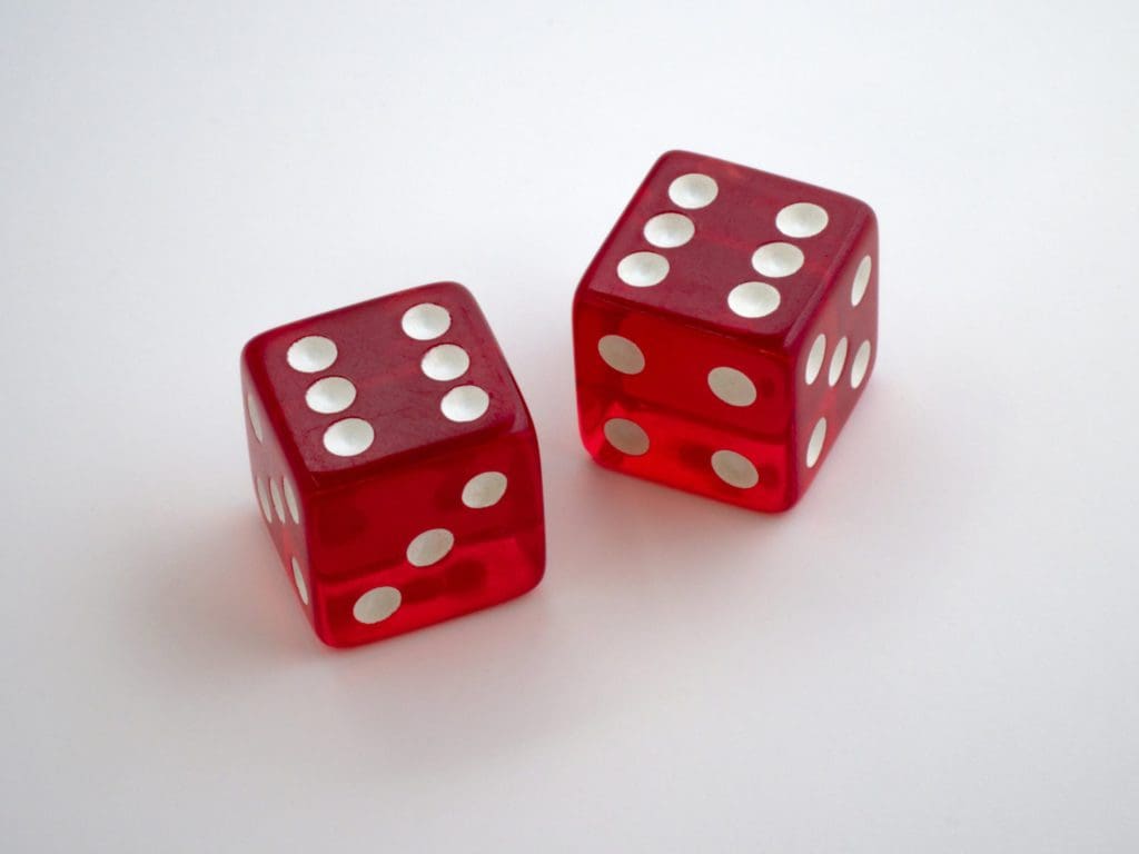 Two red translucent dice with white pips are shown on a white background. One die shows the number six, and the other shows the number five. The dice have a glossy finish, giving them a shiny appearance.